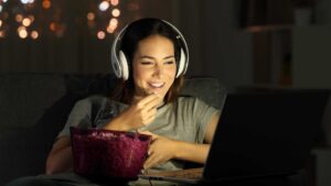 Femme qui regarde un film sur son ordinateur et mange des popcorn